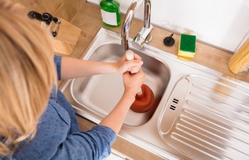 woman unclogging a sink in the kitchen